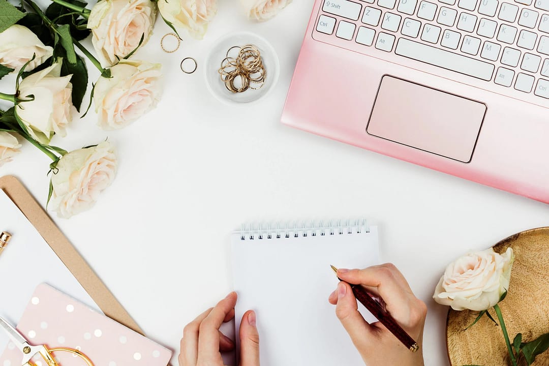 Stylish flatlay frame arrangement with pink laptop, roses, and other accessories on white. Feminine business mockup, copyspace
